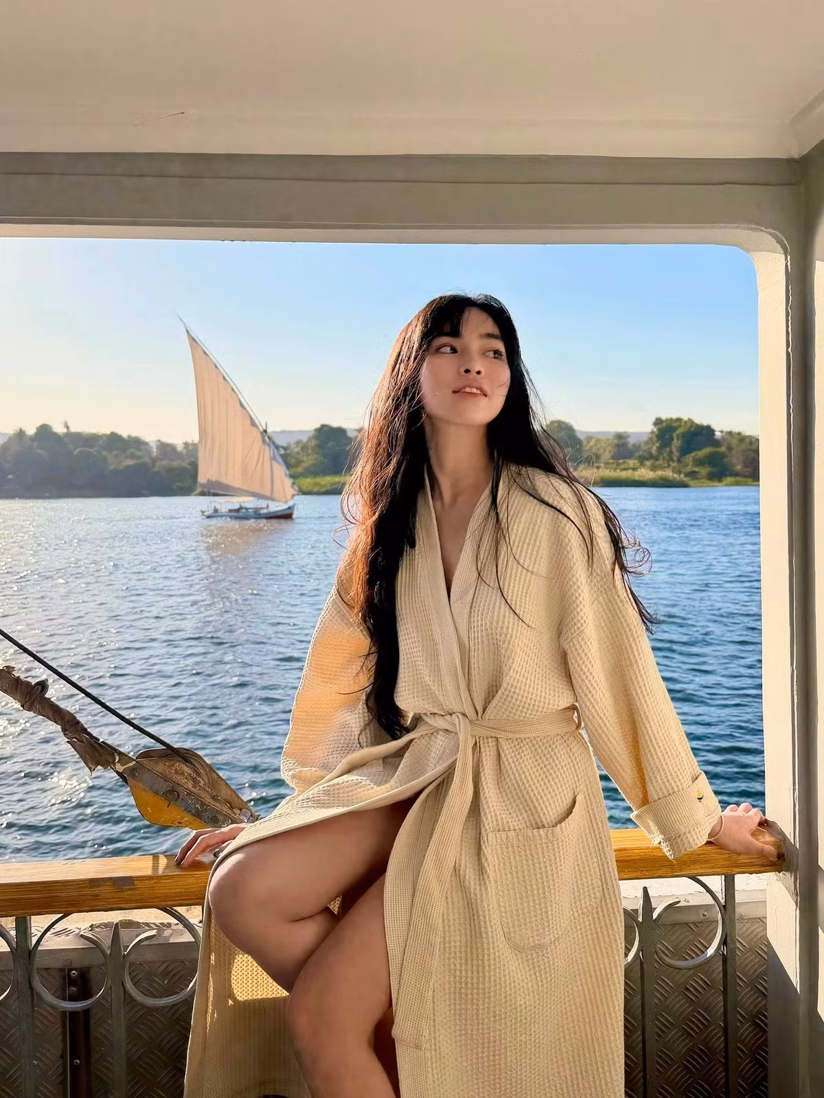 Xuất hiện trên boong thuyền, Đỗ Khánh Vân lựa chọn trang phục mang tông màu be nhẹ nhàng, thiết kế dáng choàng mềm mại với chất liệu mỏng, tạo cảm giác bay bổng và hòa hợp với cảnh sắc xung quanh.