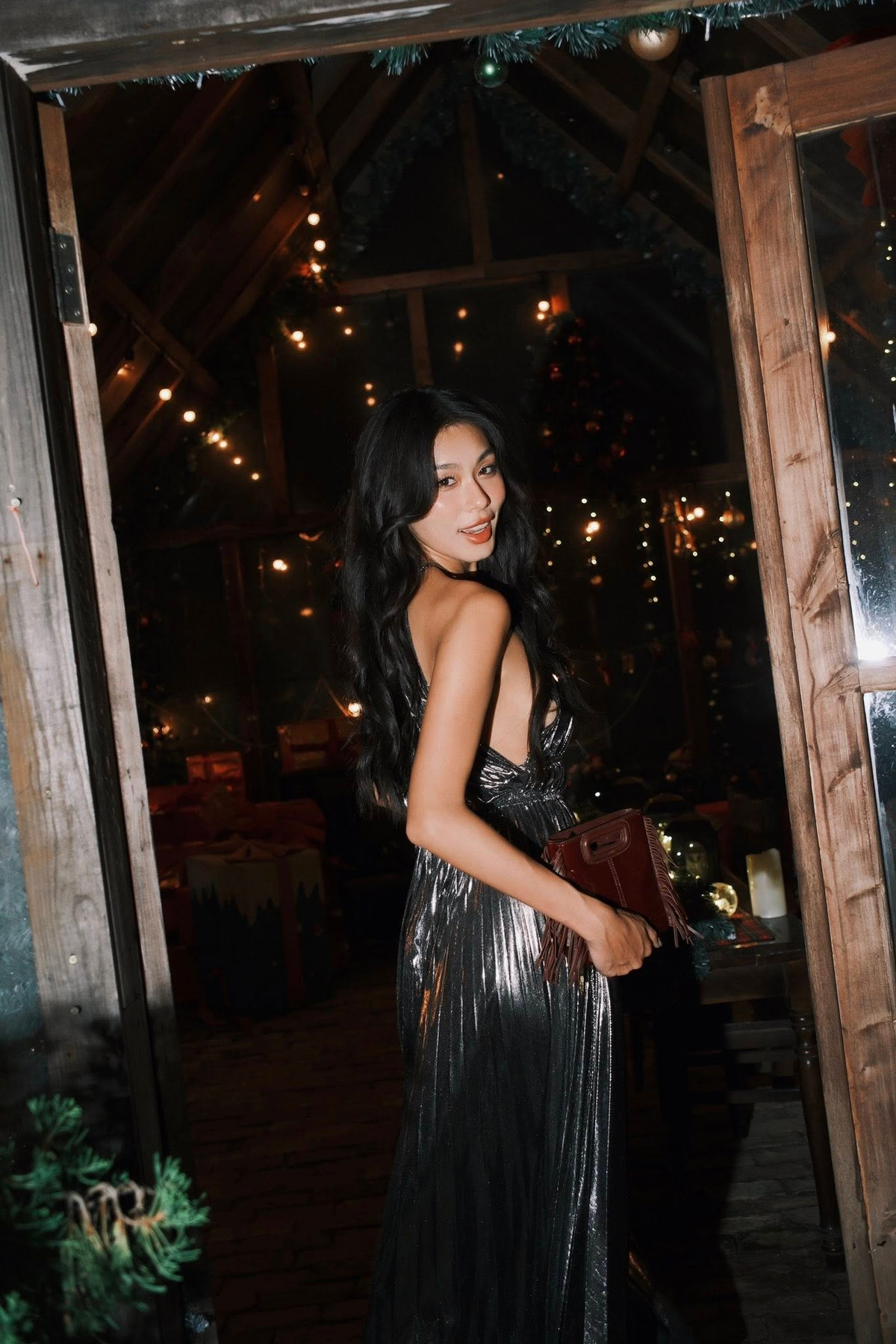 Để mở đầu mùa festive, Thảo Nhi chọn chiếc váy dạ hội ánh kim màu bạc với phom dáng mềm mại, xếp nếp tinh tế. Thiết kế cổ yếm ôm trọn bờ vai thon gọn, khoe đường cong thanh mảnh và làn da nâu khỏe khoắn đặc trưng – thứ đã trở thành “thương hiệu” của cô trong lòng công chúng. Chất liệu bắt sáng giúp mỗi chuyển động của Á hậu trở nên mềm mại nhưng đầy cuốn hút, phản chiếu ánh đèn lung linh của không gian lễ hội.