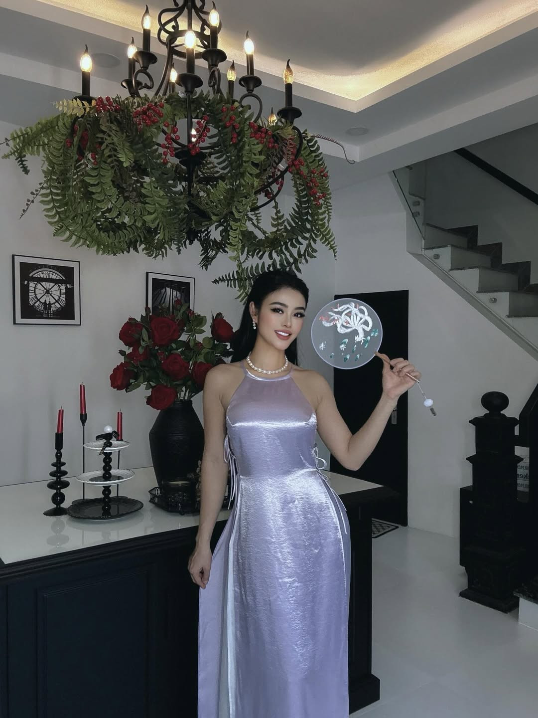 Trong loạt hình mới, Julia Hồ lựa chọn thiết kế áo dài cách tân với chất liệu ánh satin bắt sáng, phom dáng ôm nhẹ tôn lên vóc dáng gợi cảm. Gam màu tím bạc giúp tổng thể vừa mềm mại vừa hiện đại, kết hợp cùng chuỗi ngọc trai và lối trang điểm sắc sảo càng làm nổi bật thần thái sang trọng của người đẹp sinh năm 1990. Mái tóc dài suôn mượt, nụ cười rạng rỡ và cách tạo dáng nhẹ nhàng giúp cô ghi điểm với hình ảnh nữ tính nhưng không kém phần quyến rũ.