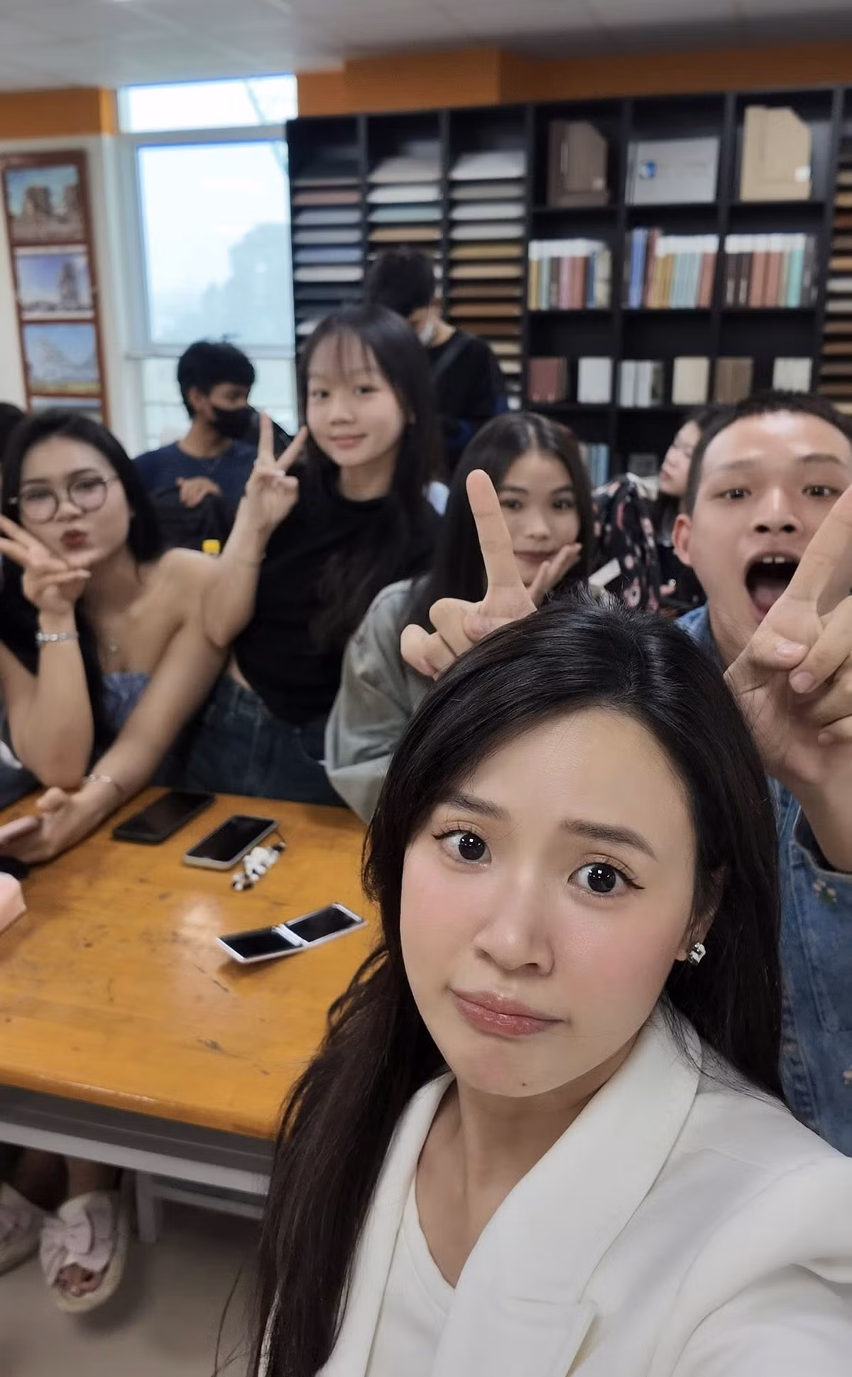 Trong hình, Midu ăn mặc giản dị, trang điểm nhẹ nhàng cùng tạo dáng "xì tin" bên học trò.