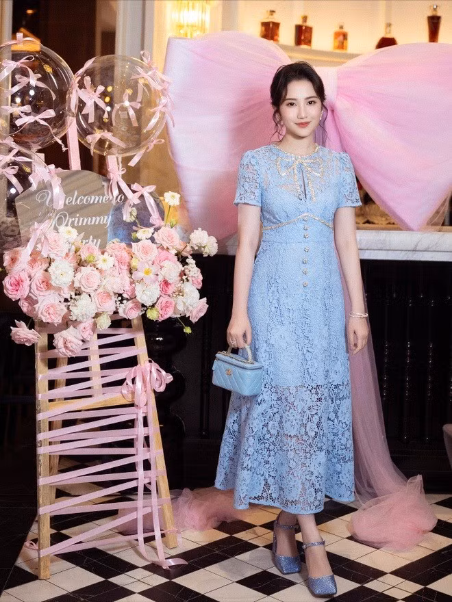 Buổi tiệc được tổ chức tại một không gian sang trọng, lấy tông màu hồng pastel làm chủ đạo. Toàn bộ bàn tiệc được trang trí ngập tràn hoa hồng và hoa cẩm tú cầu, cùng với những quả bóng bay trong suốt được thắt nơ hồng điệu đà. Điểm nhấn ấn tượng nhất chính là chiếc nơ bằng lụa màu hồng khổng lồ, tạo nên một bối cảnh chụp ảnh "tiểu thư" đúng nghĩa.