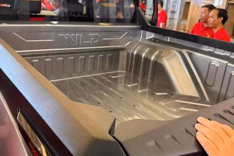 Tiếp theo đó là sự xuất hiện của cụm đèn pha hình thang ở hai góc đầu xe với kích thước khá lớn. Cản trước cũng đã được làm mới và có thêm hốc gió hình chữ nhật. Trong khi đó, ốp cản trước màu bạc của phiên bản concept đã bị loại bỏ trên VinFast VF Wild thương mại. Nằm sát với nắp ca-pô vẫn là dải đèn LED định vị ban ngày hình cánh chim đặc trưng của thương hiệu VinFast.