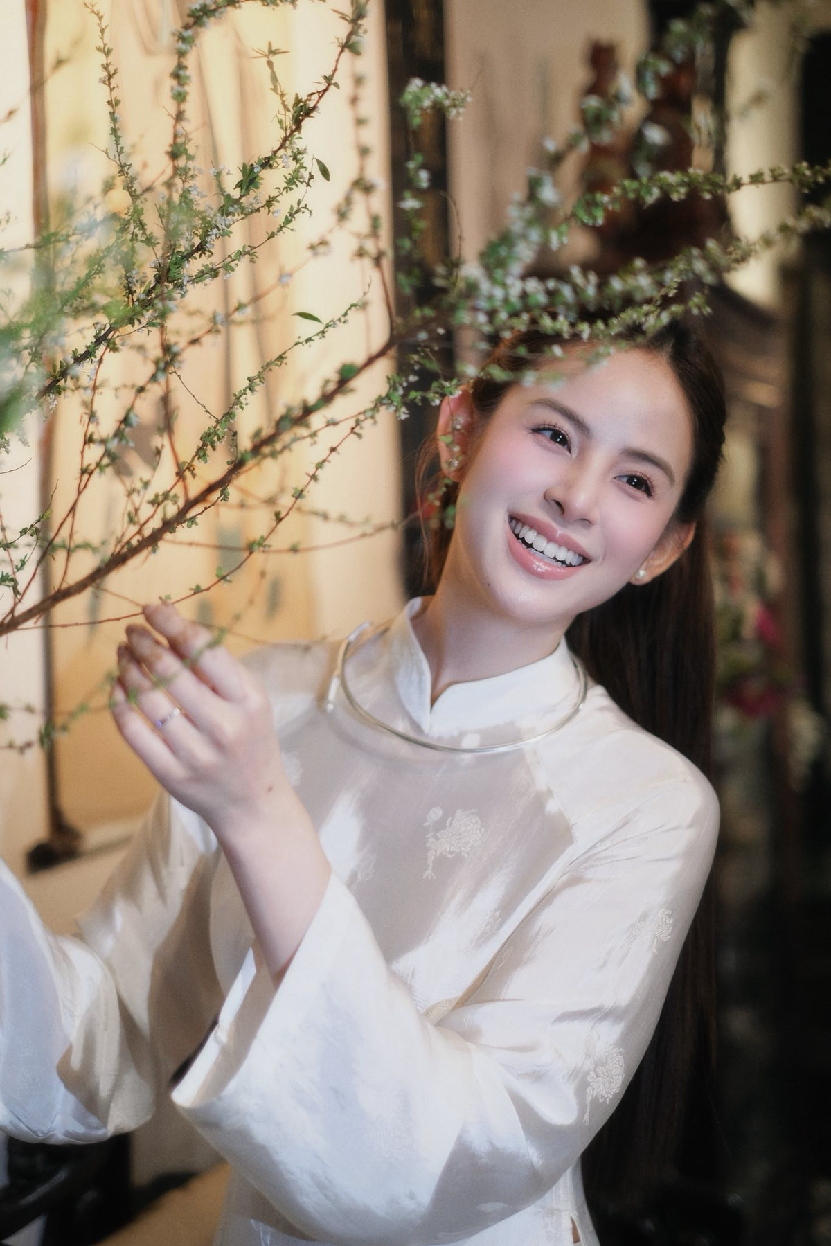 Bối cảnh chụp ảnh được lựa chọn kỹ lưỡng, khi thì là không gian bên hồ nước yên ả với cây xanh và cây cầu đỏ phía xa, khi lại là góc nhà cổ đậm chất Á Đông với tranh thủy mặc, bình hoa và nội thất gỗ trầm ấm.