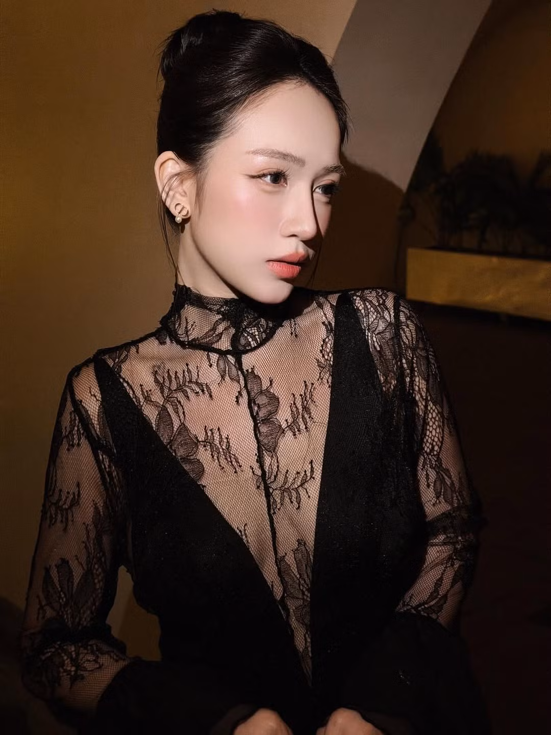 Trong bộ váy đen xuyên thấu phối ren, Joyce Phạm toát lên vẻ đẹp trưởng thành và quyến rũ. Phần cổ cao thanh lịch kết hợp tay dài ren mảnh giúp tôn bờ vai thon và làn da trắng mịn, trong khi dáng váy ôm vừa phải khéo léo khoe đường cong cân đối.