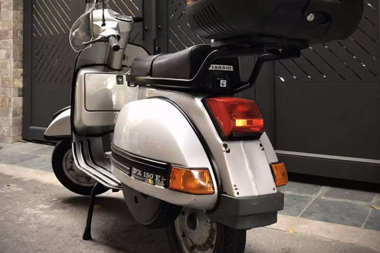 Về ngoại hình, chiếc Vespa PX150E 1995 của vẫn trung thành với kiểu dáng khung thép nguyên khối (monocoque), thân xe liền khối uốn cong mềm mại, chắn bùn trước hình cánh chim và cụm đèn pha hình tròn đặc trưng.