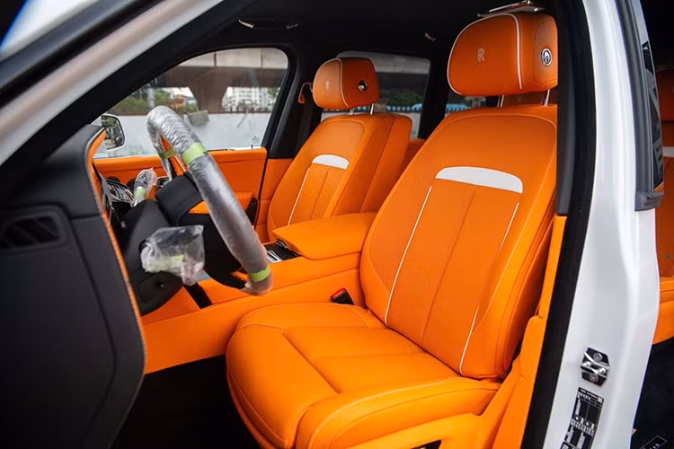 Bên trong cabin, chiếc Rolls-Royce Cullinan Black Badge 2025 sở hữu nội thất được bọc da màu cam Hermes kết hợp với một số chi tiết được ốp carbon. Phía sau vô-lăng bọc da là bảng đồng hồ kỹ thuật số cỡ lớn, màn hình thông tin trung tâm mới với giao diện giống xe điện Spectre.