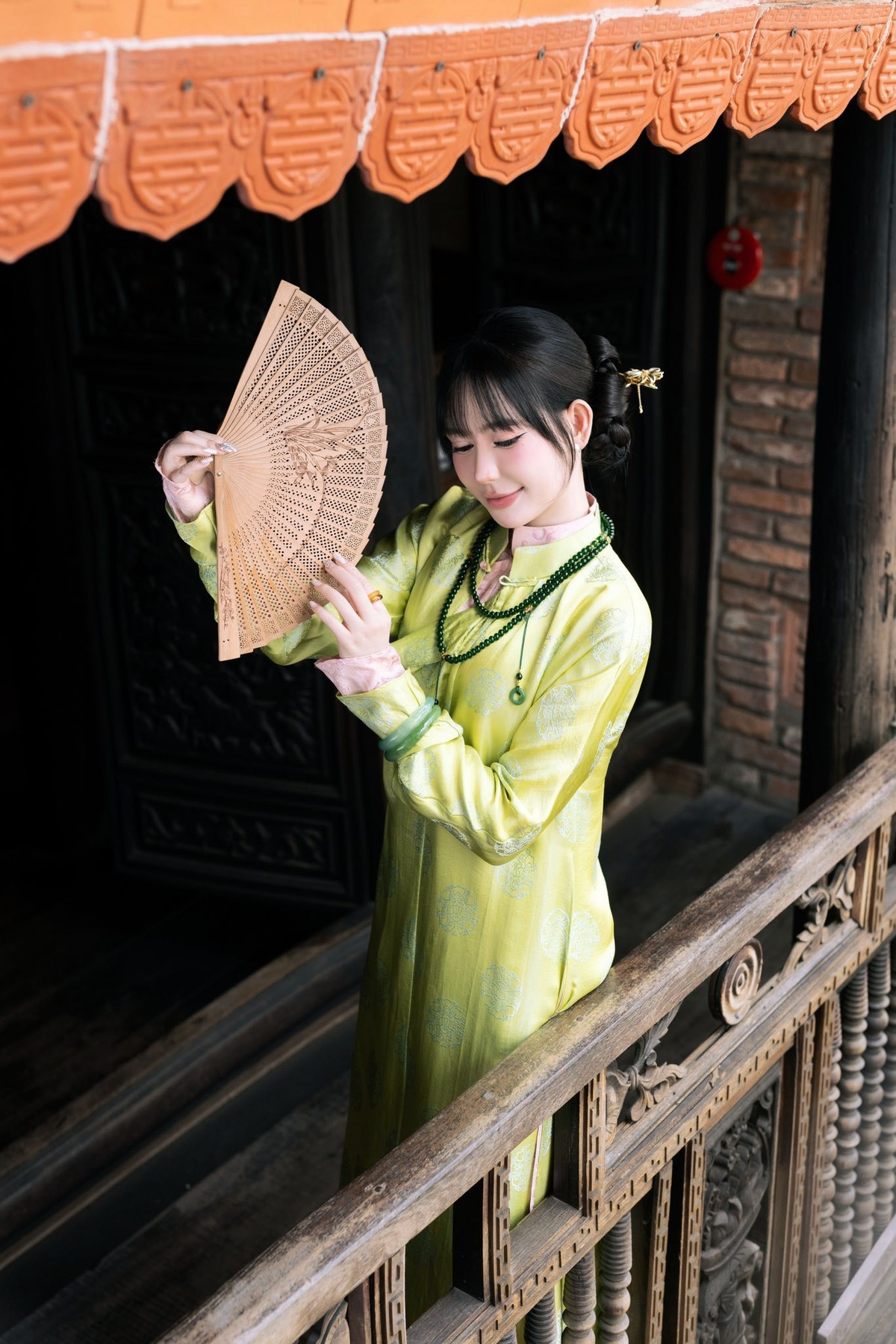 Vân Tiny khéo léo kết hợp vòng cổ hạt xanh, vòng tay ngọc và chiếc quạt gỗ nhỏ, tạo nên sự đồng điệu về màu sắc và chất liệu. Tất cả đều vừa đủ để làm nổi bật tổng thể, không gây cảm giác rườm rà hay phô trương.