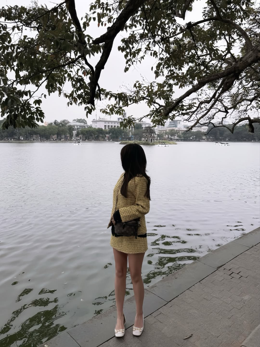 Trong loạt ảnh được chia sẻ, Kiều Trinh Xíu diện trang phục gam màu trầm ấm, thiết kế đơn giản nhưng tinh tế, giúp tôn lên sắc vóc thon gọn, thanh mảnh. Vóc dáng nhỏ nhắn cùng đôi chân dài thẳng khiến cô nàng trông như một “búp bê sống” giữa khung cảnh Hồ Gươm yên bình.