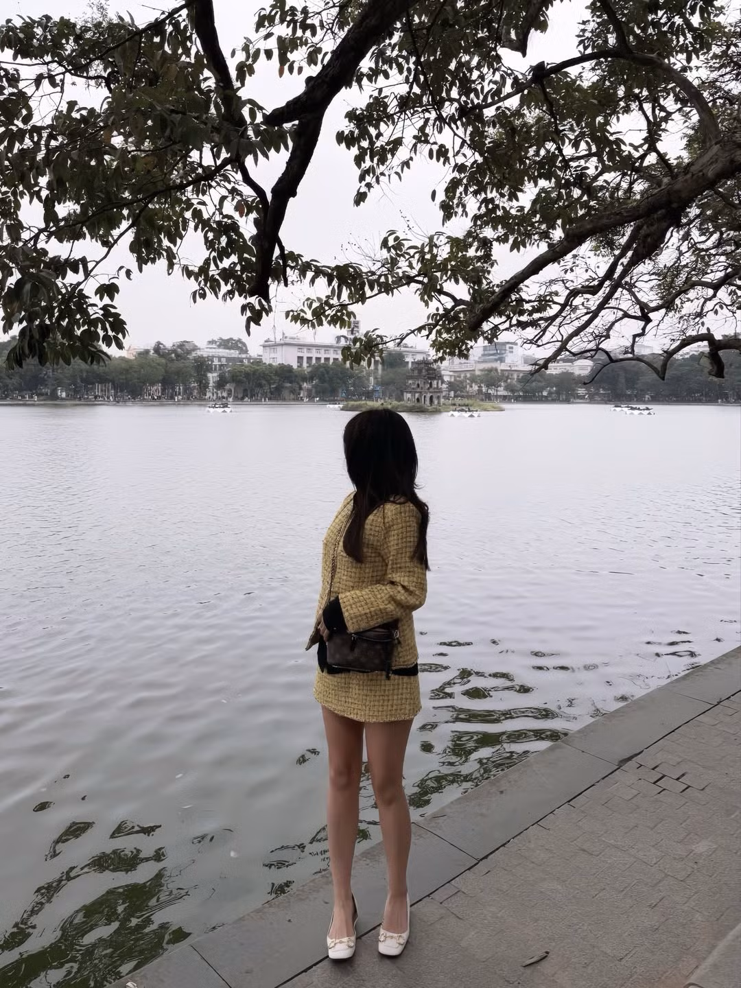 Trong loạt ảnh được chia sẻ, Kiều Trinh Xíu diện trang phục gam màu trầm ấm, thiết kế đơn giản nhưng tinh tế, giúp tôn lên sắc vóc thon gọn, thanh mảnh. Vóc dáng nhỏ nhắn cùng đôi chân dài thẳng khiến cô nàng trông như một “búp bê sống” giữa khung cảnh Hồ Gươm yên bình.