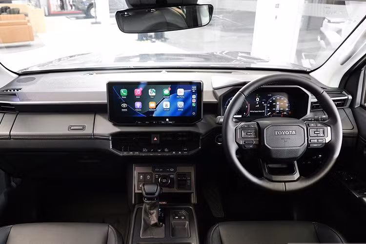 Bên trong, nội thất Hilux 2026 mang thiết kế hiện đại tương tự dòng Land Cruiser, nổi bật với bảng táp-lô trải ngang và cụm màn hình kép 12,3 inch: một cho hệ thống giải trí trung tâm và một cho cụm đồng hồ kỹ thuật số trước vô-lăng.