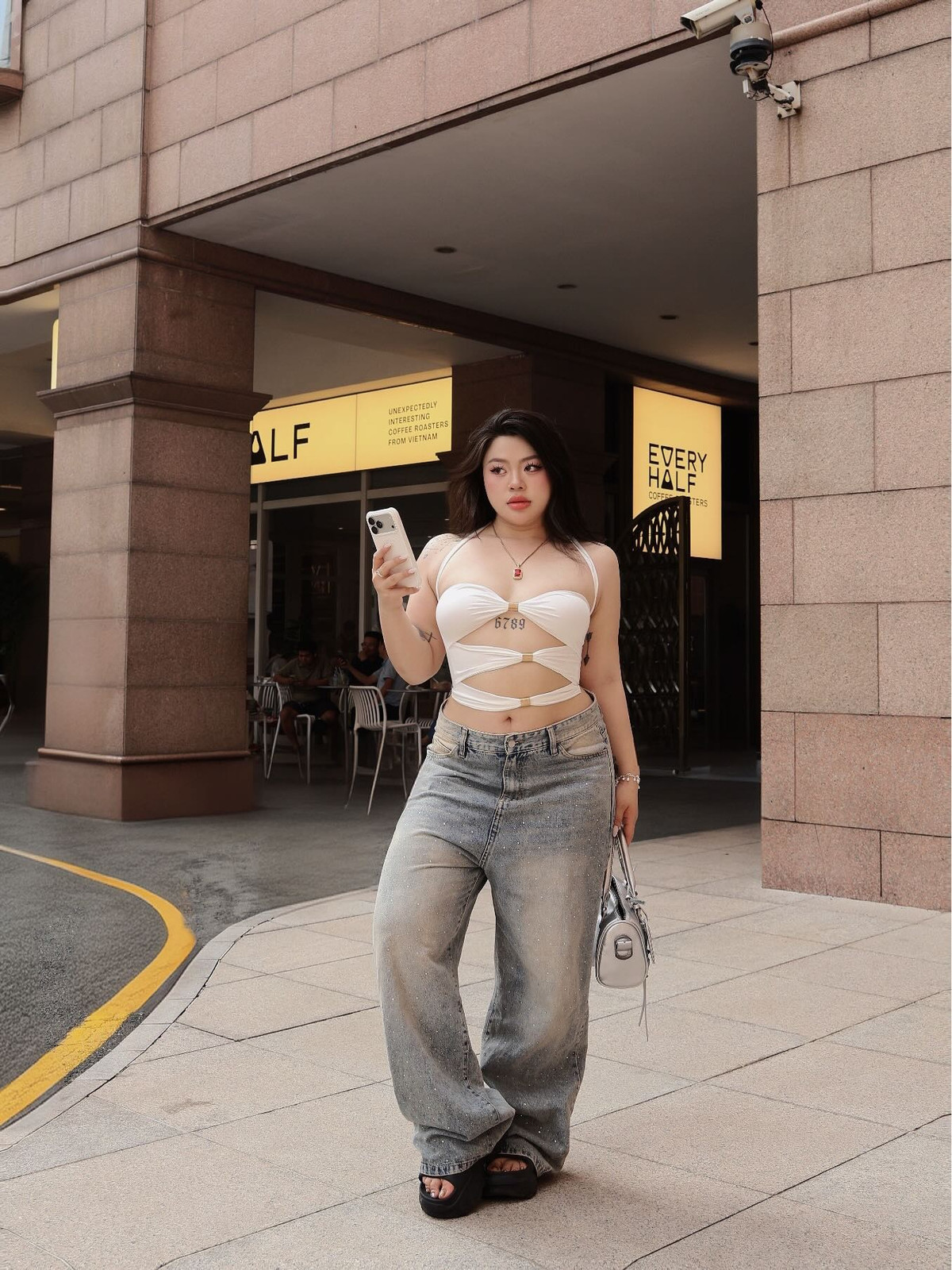 Trong loạt hình được chia sẻ, Cố Hữu Vi diện áo trắng dáng ôm với những đường cắt xẻ táo bạo ở phần eo và ngực, kết hợp cùng quần jeans ống rộng bụi bặm.