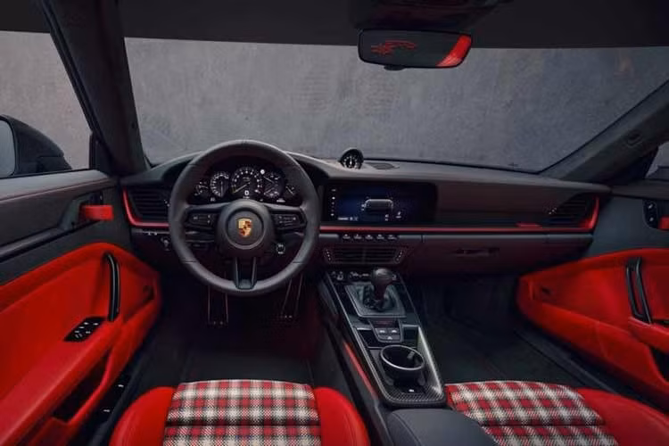 Các chi tiết bên trong nội thất của Porsche 911 GT3 S/C 2026 như chỉ khâu, tay nắm cửa và tay kéo ghế đều mang tông đỏ rực rỡ, kết hợp cùng logo 911 và ốp taplo màu đỏ Pyro Red. Đáng chú ý, bộ ghế Adaptive Sports được bọc bằng da bện bốn màu thủ công, tạo nên một kết cấu bề mặt độc lạ mà các dòng ghế đua bucket seat thông thường không có được.