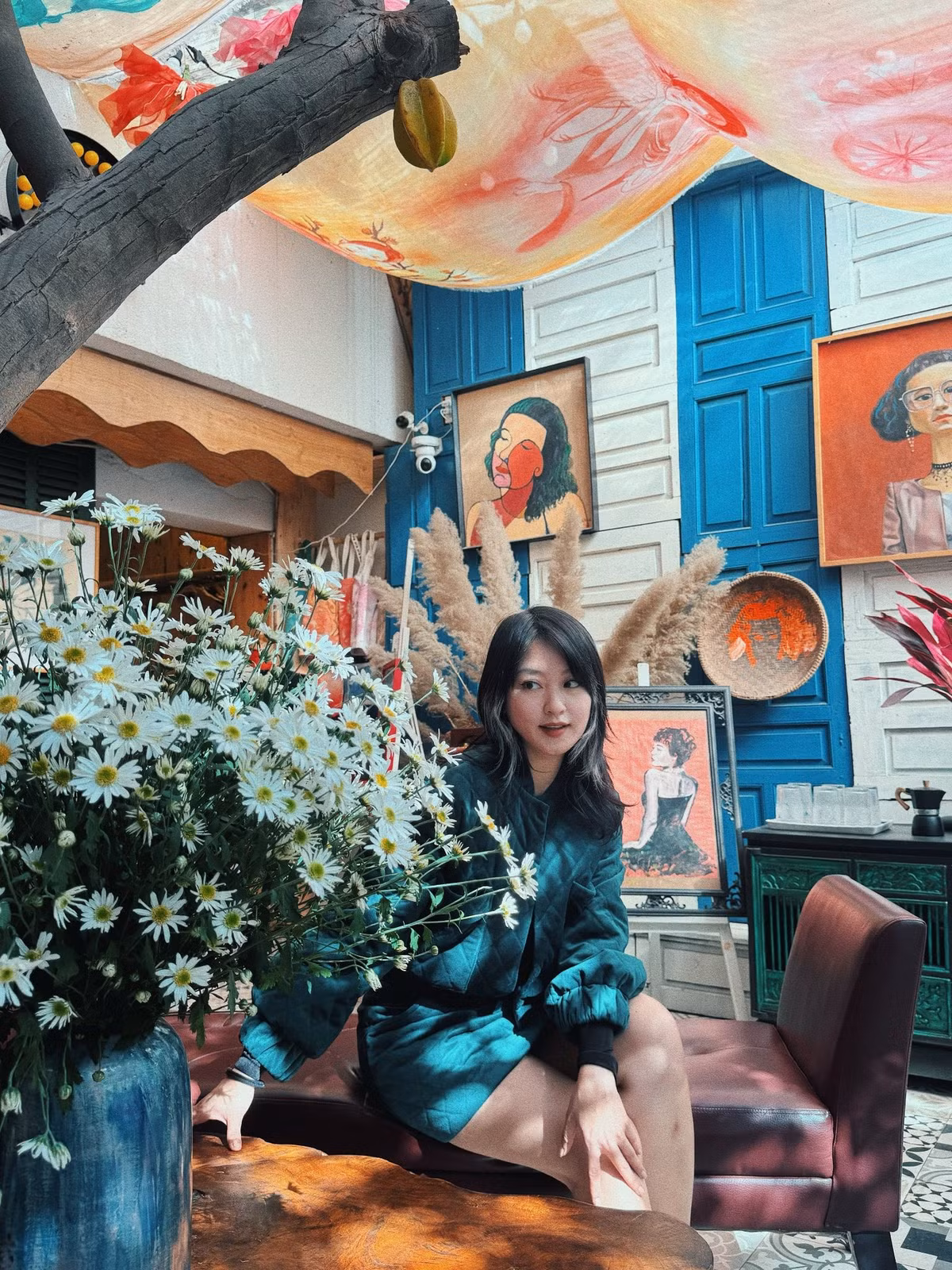 Bên cạnh đó, không gian nghệ thuật với tranh vẽ, rèm lụa và ánh sáng xuyên qua trần nhà mang lại cho bộ ảnh một chất thơ rất riêng. Những bông cúc họa mi trắng muốt đặt trong chiếc bình gốm xanh trở thành điểm nhấn, khiến vẻ đẹp của Mi Vân thêm phần tinh khôi và giàu cảm xúc.