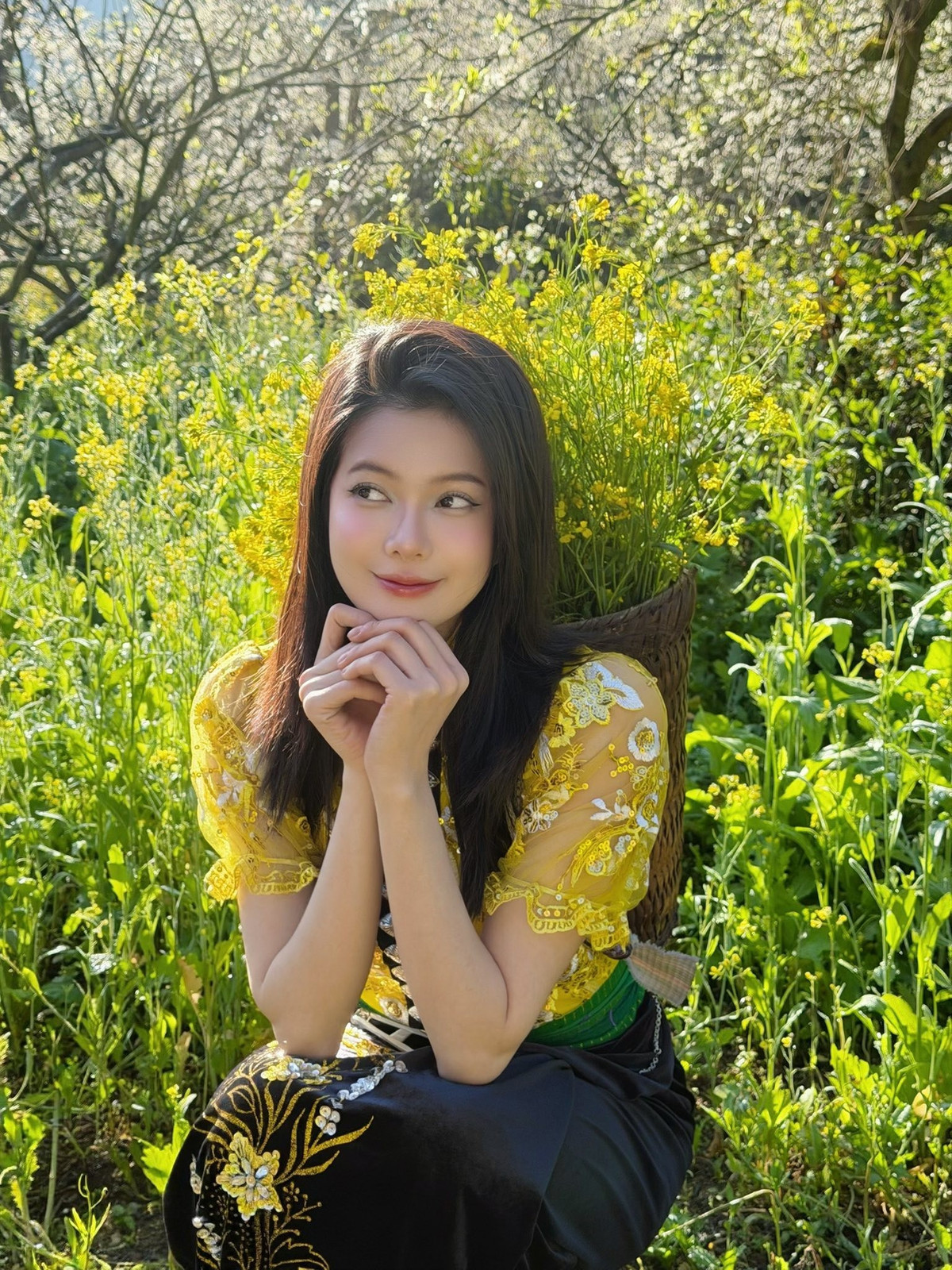 Áo có phom dáng ôm gọn, cổ cao đặc trưng, điểm xuyết những đường thêu tinh xảo và họa tiết ánh kim nổi bật trên nền vải vàng tươi. Phần tay áo voan mỏng, thêu hoa cầu kỳ giúp tổng thể trở nên nhẹ nhàng, nữ tính.