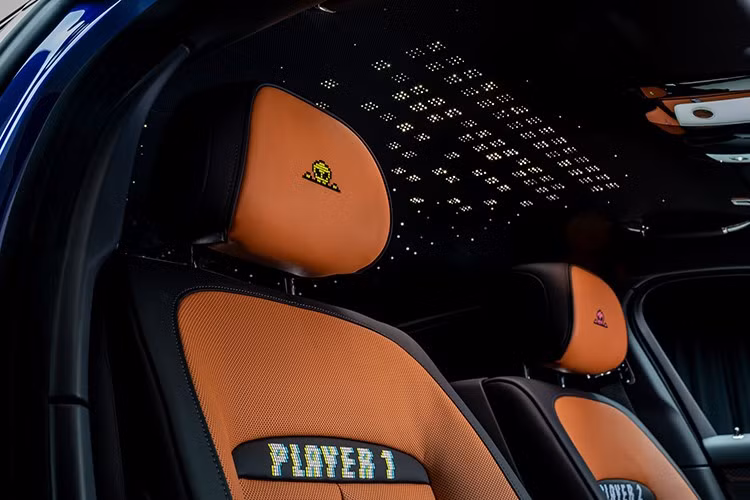 Trên bậc cửa của xe có loạt hiệu ứng nhấp nháy quen thuộc trong game cổ điển như “Press Start”, “Insert Coin”, “Loading” và “Level Up” mang đến trải nghiệm giống như đang bước vào một máy arcade. Xe còn có bàn ăn gấp phía sau lưng hàng ghế trước cũng được khắc họa hình Cheeky Alien.