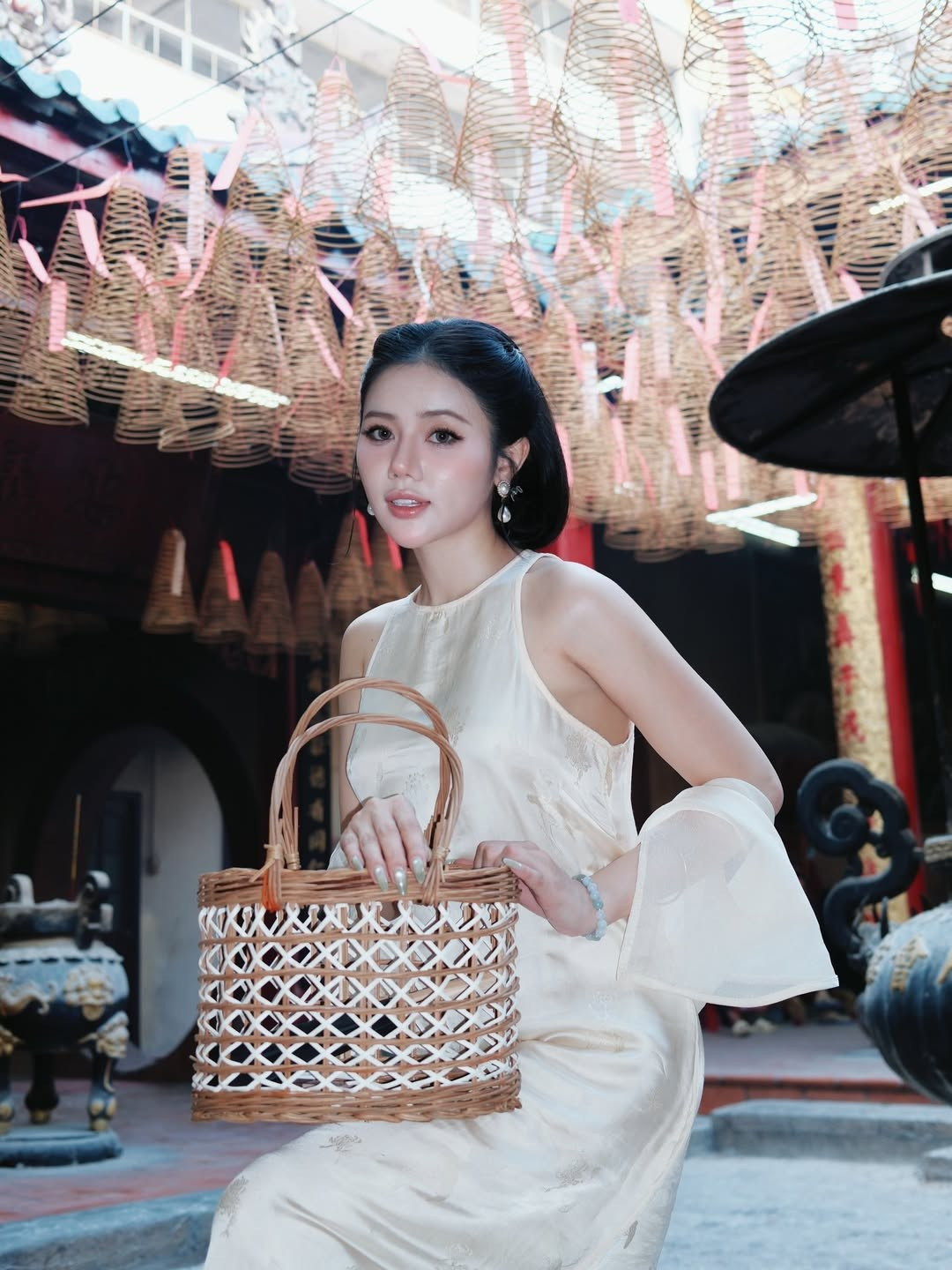 Trong loạt ảnh mới chia sẻ trên mạng xã hội, Bò Chảnh lựa chọn phong cách kín đáo nhưng vẫn tôn lên vẻ nữ tính. Thiết kế áo lụa suông nhẹ, chất vải mềm rủ tự nhiên giúp cô toát lên hình ảnh thanh lịch, nền nã. Gam màu trắng kem không chỉ tôn da mà còn hòa hợp với bối cảnh cổ kính của khu phố người Hoa – nơi nổi tiếng với những mái ngói cong, họa tiết rồng phượng và đèn lồng đỏ treo cao.