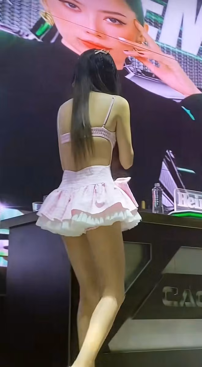 Thiết kế dáng ngắn, ôm nhẹ cơ thể, kết hợp cùng những chi tiết bèo nhún và lớp váy xếp tầng nhằm tạo cảm giác trẻ trung, đáng yêu. Nam Em còn hoàn thiện tổng thể bằng loạt nơ nhỏ đính trên mái tóc dài, góp phần "hack tuổi" rõ rệt.