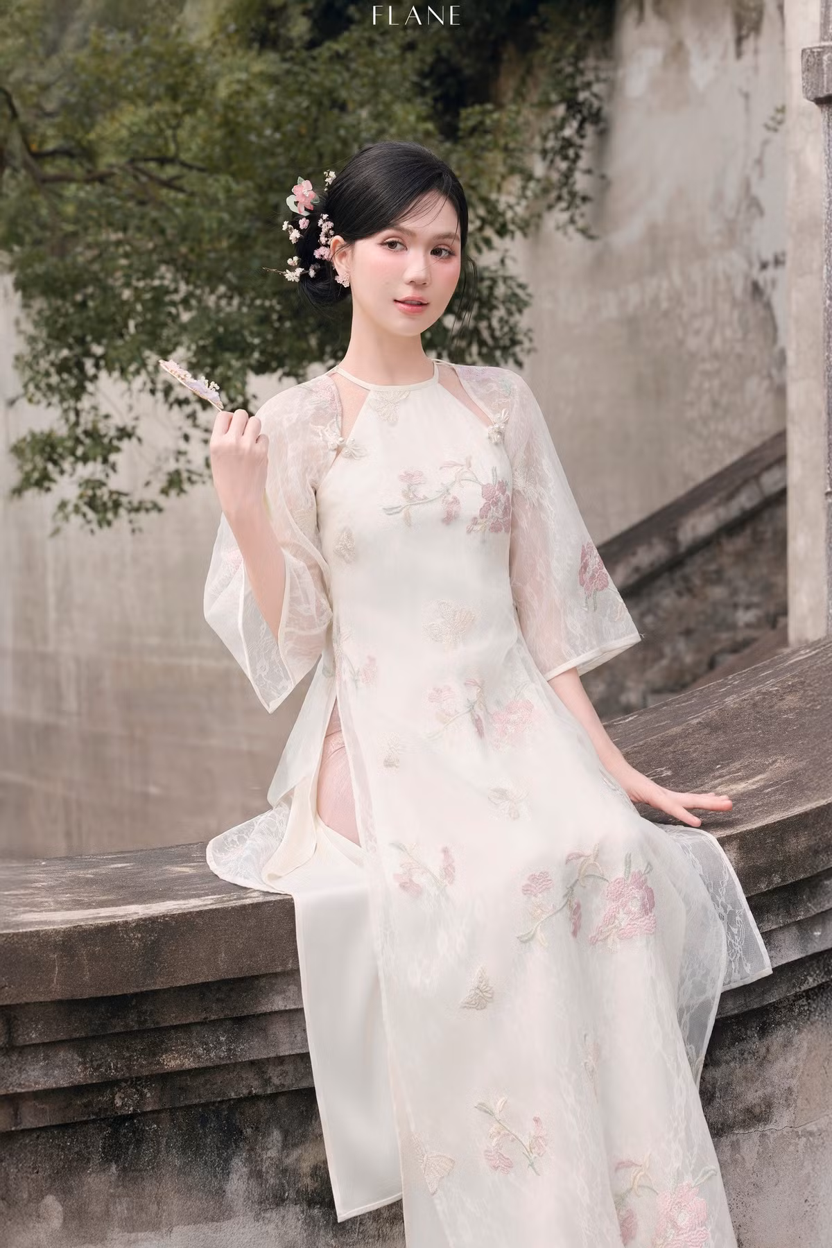 Trong loạt ảnh mới đây, Ngọc Trinh diện tà áo dài tông trắng ngà, điểm họa tiết hoa thêu pastel, giúp tôn lên vẻ mềm mại, nền nã và nữ tính của người đẹp Trà Vinh.