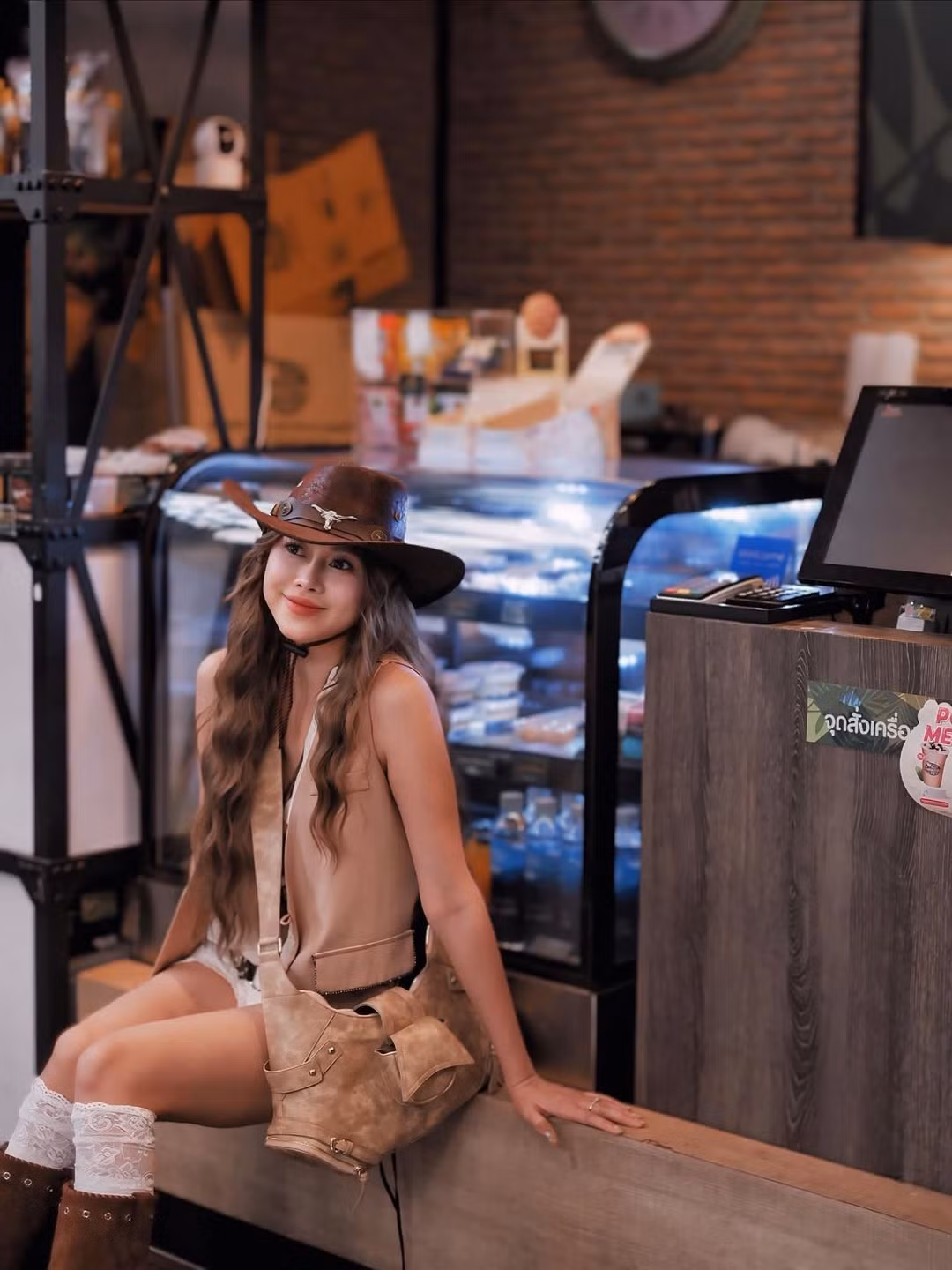 Cô nàng đội chiếc mũ cao bồi da nâu có hoạ tiết kim loại nổi bật, làm điểm nhấn cho tổng thể. Phần tóc uốn sóng dài nhẹ nhàng khiến diện mạo thêm phần gợi cảm nhưng vẫn giữ nét trẻ trung.