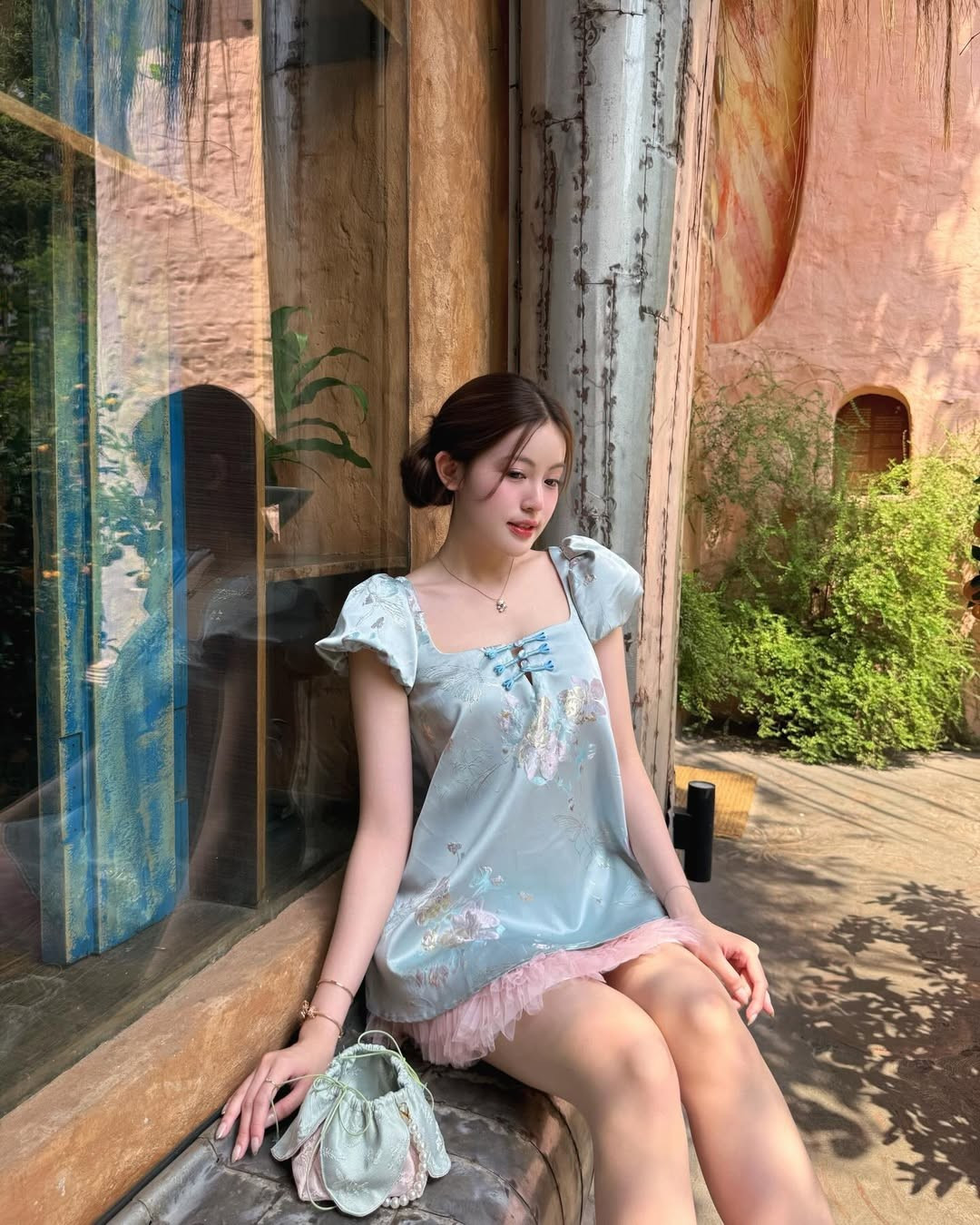 Ở một vài khung hình ngoài trời, Tăng Mỹ Hàn đứng giữa những chậu cây và bụi hoa rực rỡ, phía sau là bức tường vàng cam đậm chất Á Đông. Khung cảnh này gợi liên tưởng đến những góc phố, quán cà phê quen thuộc mỗi dịp Tết, nơi giới trẻ thường tìm đến để chụp ảnh xuân.