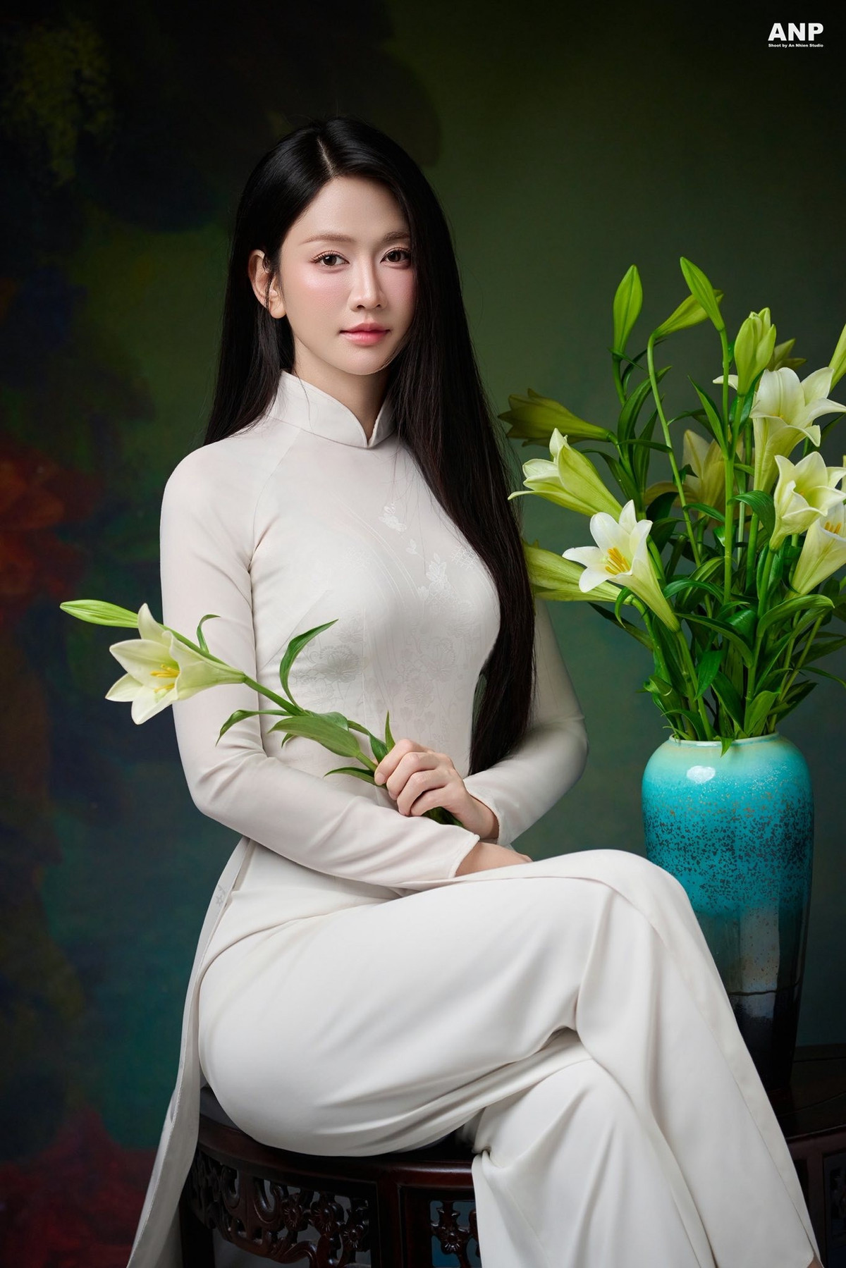 Trong loạt hình, Lê Bống lựa chọn áo dài trắng trơn, phom dáng truyền thống, ôm vừa vặn cơ thể nhưng vẫn giữ được nét kín đáo, mềm mại. Gam màu trắng ngà dịu mắt kết hợp cùng chất liệu rủ nhẹ giúp tổng thể trang phục toát lên vẻ thanh tao, đúng tinh thần của hình tượng thiếu nữ Việt trong hội họa cổ điển.