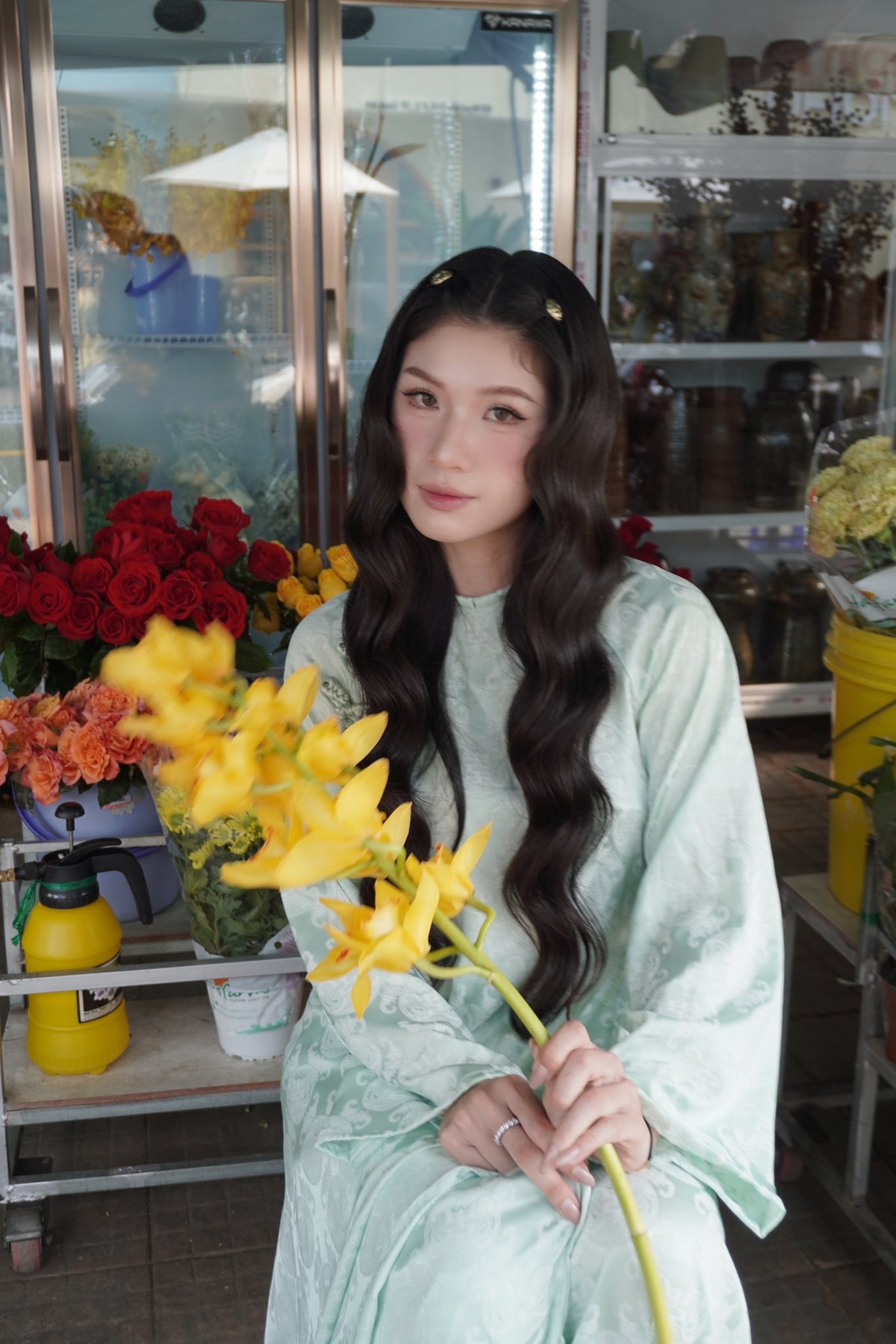 Vốn quen thuộc với hình ảnh mạnh mẽ trên sàn đấu Kumite, Trang Cẩm Lành lần này lại ghi dấu ấn bằng phong thái hoàn toàn trái ngược. Trong tà áo dài tông xanh ngọc nhạt, chất liệu mềm rủ cùng họa tiết chìm tinh tế, cô toát lên vẻ dịu dàng, thanh thoát đậm chất Á Đông. Mái tóc dài uốn nhẹ buông lơi càng tôn lên đường nét gương mặt hài hòa, ánh mắt trong trẻo và thần thái nhẹ nhàng.