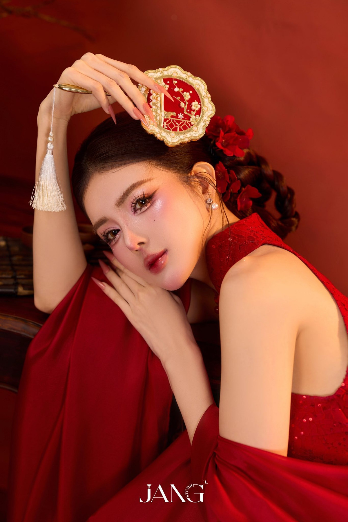 Lối trang điểm tông hồng – đỏ hài hòa cùng kiểu tóc búi gọn, điểm xuyết hoa đỏ phía sau càng làm tôn lên vẻ đẹp kiêu sa, cổ điển.