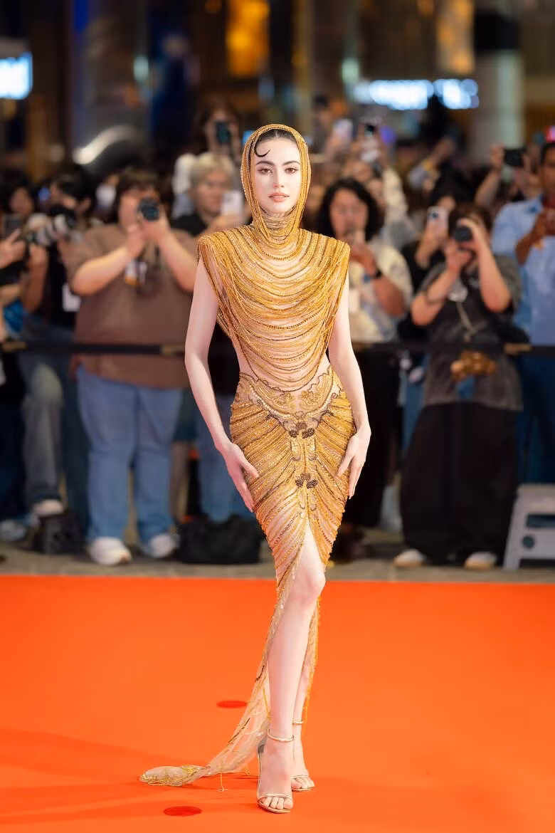 Điểm nhấn của màn xuất hiện này chính là bộ váy ánh vàng đến từ NTK Việt Nam - Lê Thanh Hoà. Thiết kế thuộc bộ sưu tập Golden Heritage, lấy cảm hứng từ nghệ thuật Champa, nổi bật với chi tiết đính kết thủ công cầu kỳ.