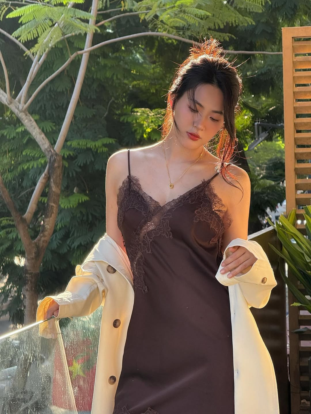 Trong bộ ảnh, Nguyễn Minh Trang diện một thiết kế váy lụa hai dây (slip dress) màu nâu sô-cô-la đầy tinh tế. Điểm nhấn của bộ trang phục là những chi tiết phối ren tỉ mỉ ở phần ngực, tăng thêm vẻ nữ tính và sang trọng.