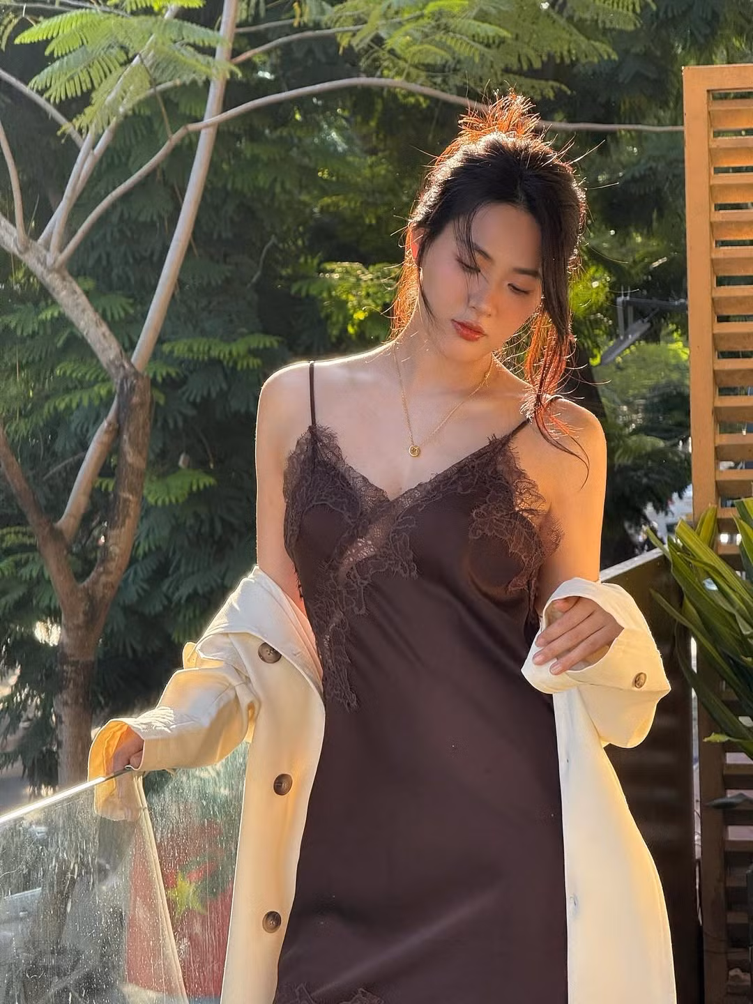 Trong bộ ảnh, Nguyễn Minh Trang diện một thiết kế váy lụa hai dây (slip dress) màu nâu sô-cô-la đầy tinh tế. Điểm nhấn của bộ trang phục là những chi tiết phối ren tỉ mỉ ở phần ngực, tăng thêm vẻ nữ tính và sang trọng.