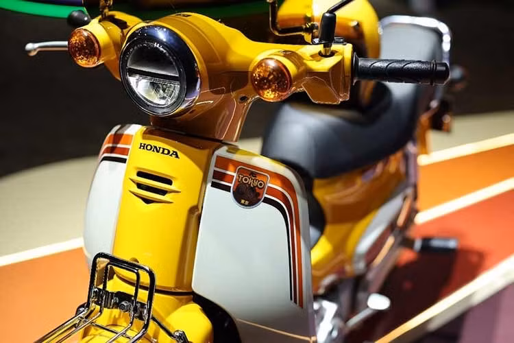Phiên bản giới hạn Honda Super Cub Tokyo 80s mới được phối màu trắng và vàng, tô điểm bởi các họa tiết đồ họa sống động trên toàn bộ xe. Những họa tiết này lấy cảm hứng từ các biển quảng cáo, đèn đường và các thiết kế pop art phổ biến ở Nhật Bản trong những năm 1980.