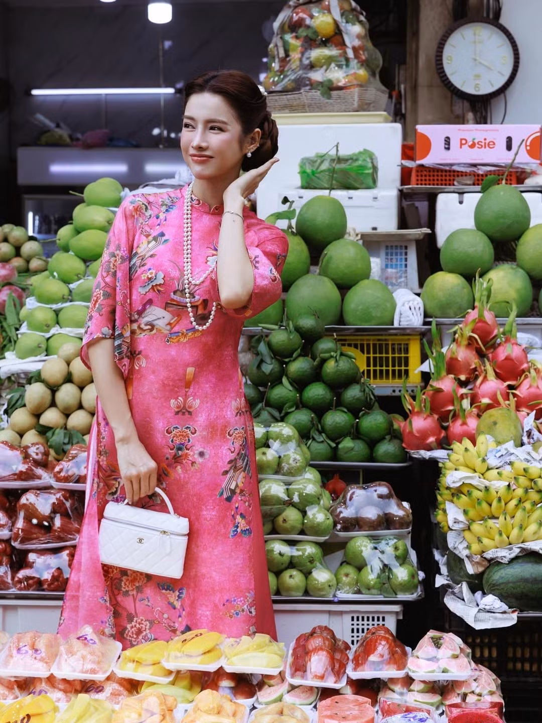 Bộ ảnh cũng cho thấy một xu hướng thú vị: áo dài không chỉ dành cho dịp lễ hay sự kiện trang trọng, mà hoàn toàn có thể xuất hiện giữa đời sống thường nhật. Khi được phối hợp khéo léo, áo dài trở thành trang phục street style đầy bản sắc, giúp người mặc nổi bật mà vẫn giữ nét dịu dàng đặc trưng. Hình ảnh người đẹp thong dong giữa phố, tay cầm bó hoa hay dừng lại chọn trái cây, gợi cảm giác gần gũi thay vì xa cách.