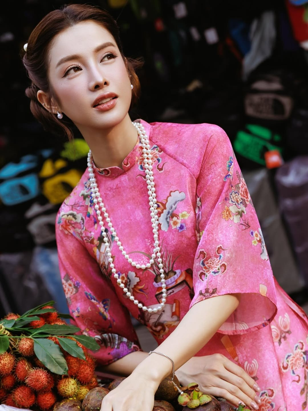 Điểm thú vị của bộ ảnh của Mỹ Duyên nằm ở bối cảnh rất đời: sạp trái cây, quán ăn bình dân, bảng hiệu cũ kỹ, xe máy đậu sát lề đường. Những khung hình được ghi lại gần khu vực Chợ Bến Thành mang đậm chất Sài Gòn – nơi quá khứ và hiện tại luôn song hành. Giữa không gian đó, tà áo dài của nữ diễn viên thướt tha bay nhẹ theo từng bước chân tạo nên sự đối lập đầy thi vị: truyền thống giữa nhịp sống hiện đại.