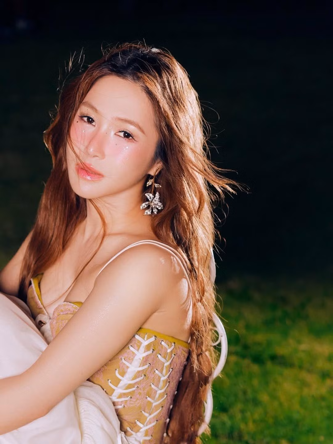 Đặc biệt, thần thái của nữ ca sĩ trong bộ ảnh—khi ngồi trên capo chiếc xe cổ, lúc tựa vào chiếc bàn gỗ giữa đồng cỏ đêm—đều toát lên sự tự chủ và mềm mại của một người phụ nữ sau nhiều trải nghiệm. Biểu cảm vừa mong manh, vừa cuốn hút giúp Hương Tràm tỏa sáng đúng chất “nàng thơ quyến rũ” trong MV mới.