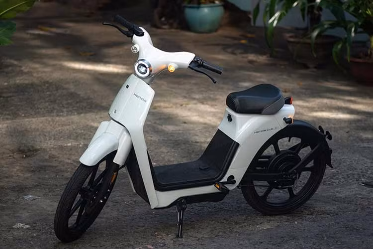 Pin của xe máy điện Honda Cub E sẽ được đặt dưới bệ để chân và không có cốp để đồ, bù lại sẽ có một móc treo đồ phía trước. Ngoài ra, xe còn được trang bị cả bàn đạp để người điều khiển dùng khi hết pin giữa đường.