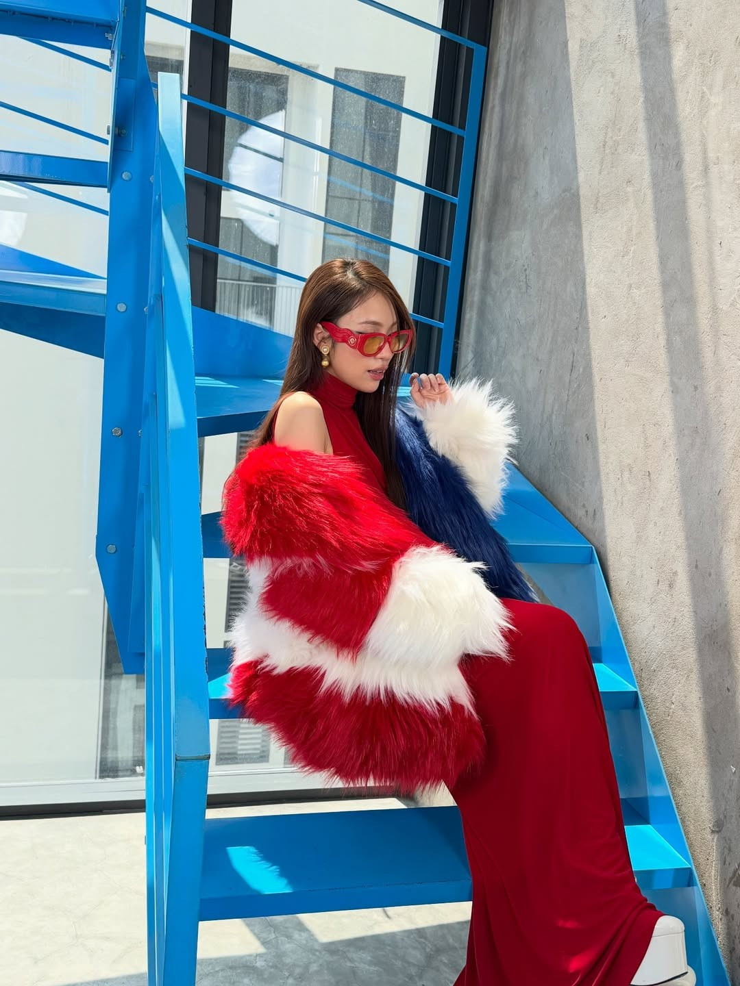 Giữa không gian cầu thang kim loại xanh dương mang hơi hướng kiến trúc hiện đại, Khánh Vy xuất hiện với thần thái tự tin, ánh nhìn sắc sảo và phong cách tạo dáng chuyên nghiệp không thua kém người mẫu.