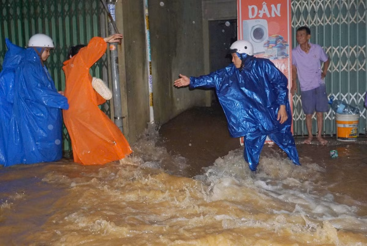 Người dân phải hợp sức dìu nhau qua dòng nước để tránh bị cuốn trôi.