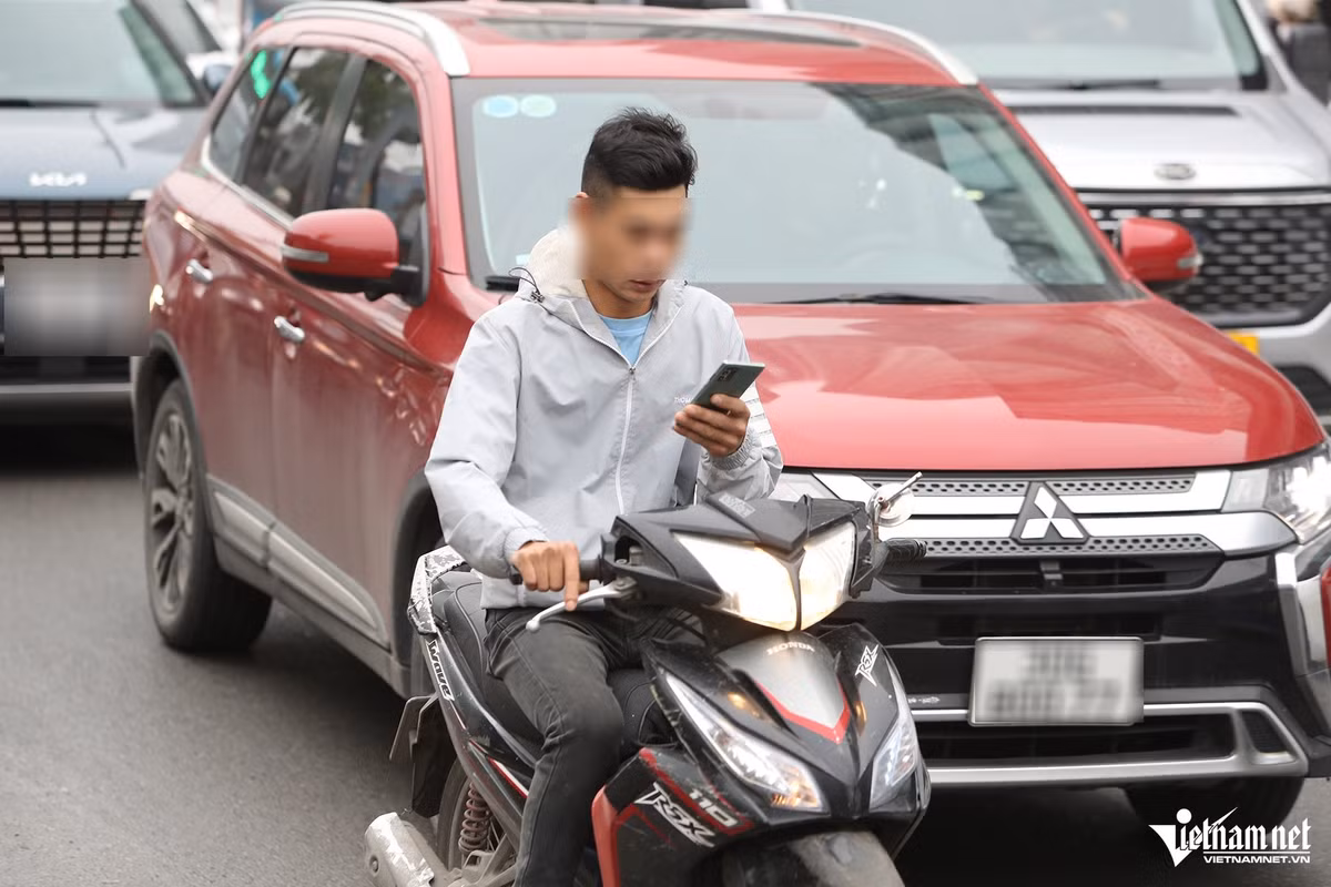 Không chỉ sử dụng điện thoại, người đàn ông điều khiển xe máy nhãn hiệu Honda Wave RSX còn không đội mũ bảo hiểm.