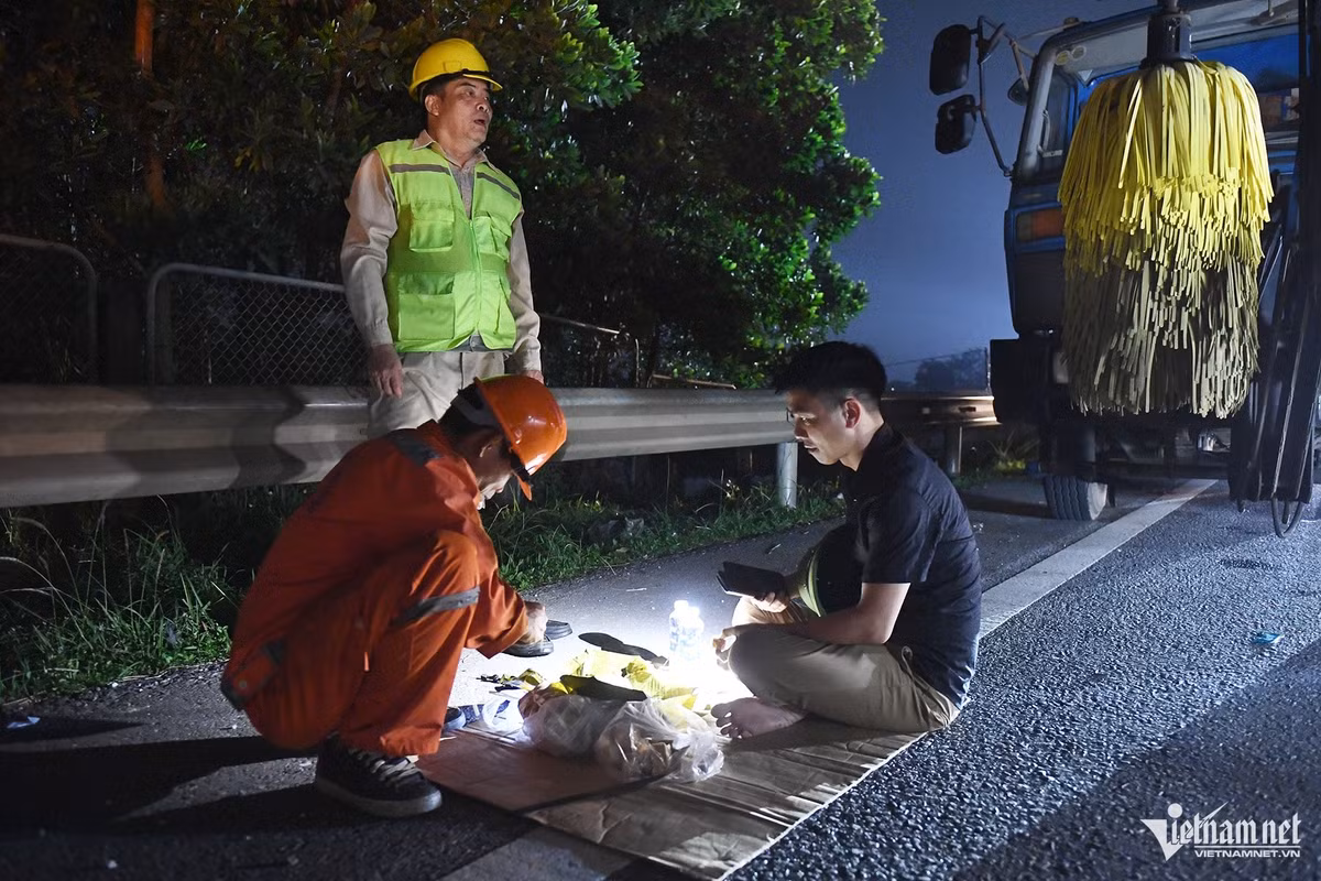 Nhóm công nhân một công ty quản lý đường bộ thay phiên nhau túc trực khu vực đầu đoạn ngập đã hai ngày nay.