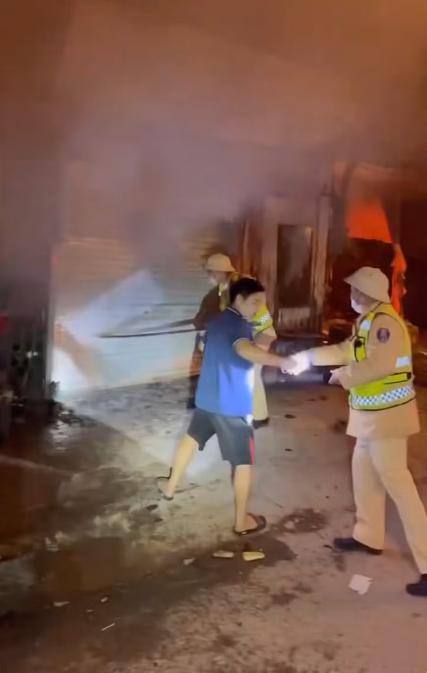 CSGT cùng người dân phá cửa, hỗ trợ giải cứu 11 người trong 2 nhà ra ngoài an toàn trước khi lửa khói bịt kín các lối thoát hiểm.