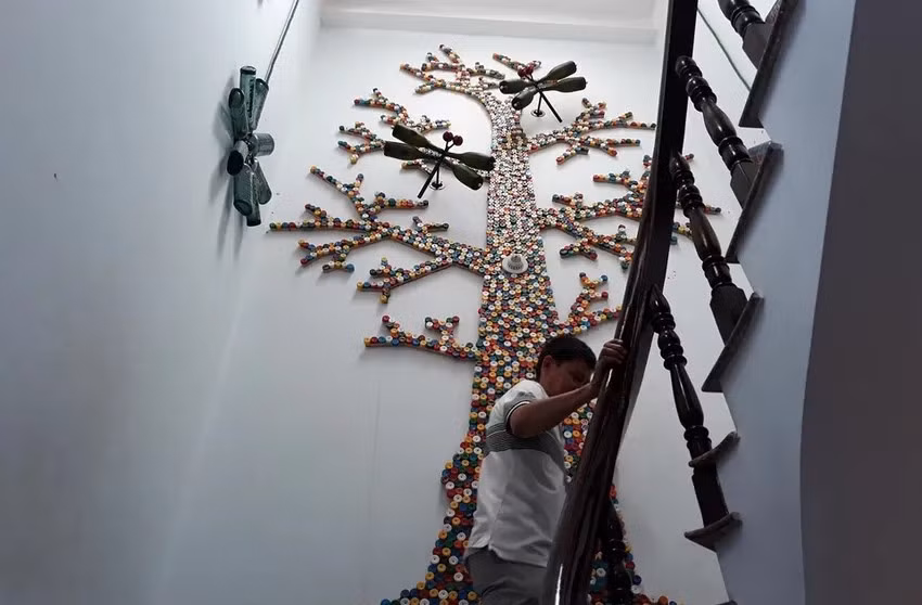 Một "cây gia đình" lớn khác cao hơn 4 m, được ghép ngay cầu thang tầng 3 bởi hàng ngàn nắp chai đủ màu sắc. Ảnh: Znews