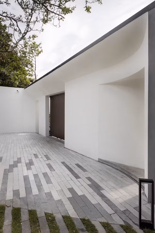 Tường rào được thiết kế cong và khe sáng giúp bề mặt tưởng chừng cứng nhắc trở nên mềm mại và sống động hơn. Ảnh: Goku Agency
