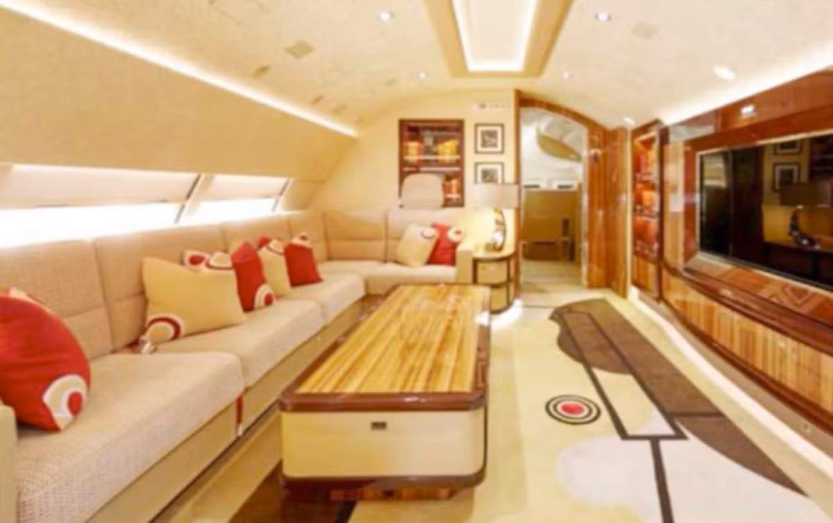 Phòng khách ở tầng trên của máy bay Boeing 747-8 có ghế sofa hình chữ L, giá sách âm tường và TV màn hình lớn. Ảnh: AMAC