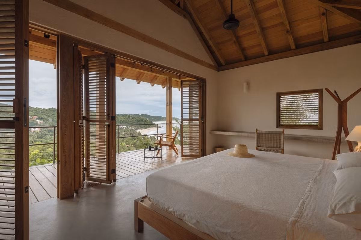 Phòng ngủ mở ra ban công lớn, với cửa gỗ xếp và tầm nhìn bao quát biển. Ảnh: Archello
