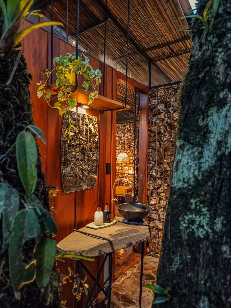 Bồn rửa mặt đặt ngoài trời với bàn đá thô, chậu sứ tối màu và tường gỗ, tạo cảm giác gần gũi thiên nhiên. Ảnh: Archdaily