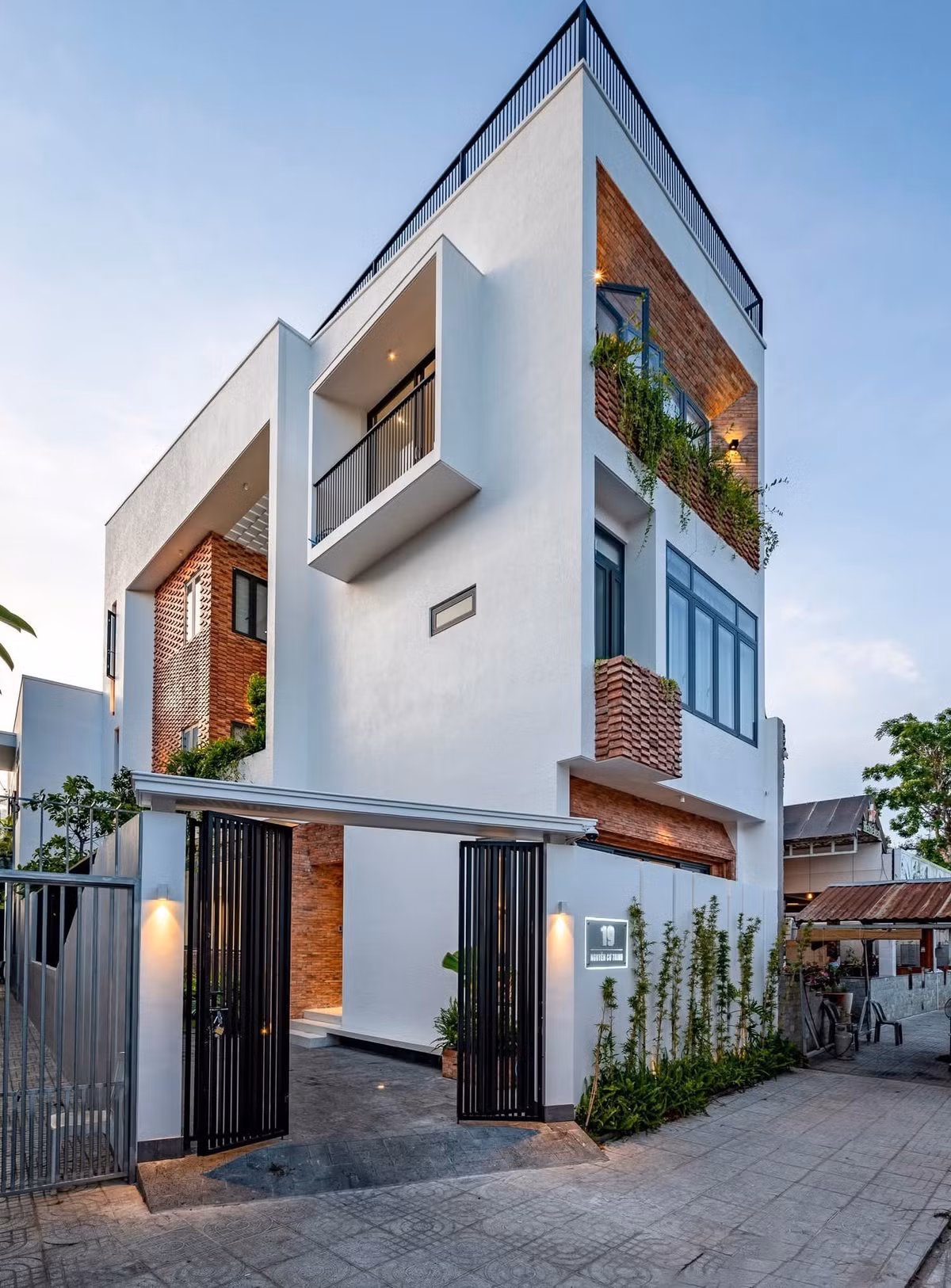Nằm tại Bà Rịa - Vũng Tàu, ngôi nhà 3 tầng nổi bật với mặt tiền sơn trắng, điểm thêm chất hoài cổ của gạch nung đỏ. Ảnh: Lilo Studio