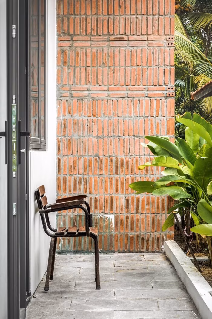 Bức tường gạch đỏ nhuốm màu thời gian, gợi nhắc nét làng quê xưa. Ảnh: Minq Bùi