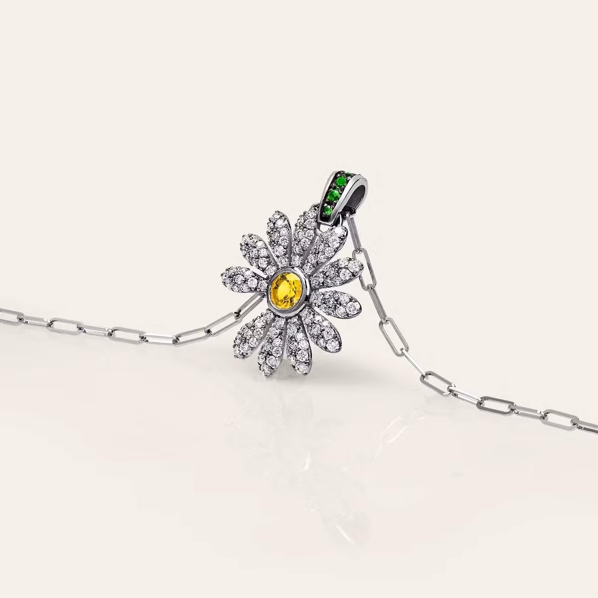 Mặt dây chuyền được chế tác thủ công từ 5,55 gr vàng trắng 18K, đính 110 viên kim cương trắng nặng tổng cộng 0,47 carat ở phần cánh hoa, một viên kim cương vàng 0,3 carat làm nhụy, và 4 viên đá tsavorite xanh lá nổi bật. Ảnh: Jacob &amp; Co.