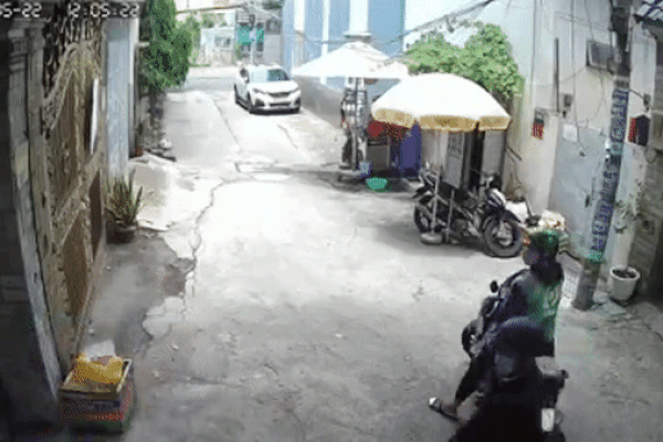 Theo camera ghi lại, người phụ nữ chạy xe máy tay ga màu đỏ rẽ vào một con hẻm. Lúc này, thanh mặc áo xe ôm công nghệ điều khiển xe máy, chở theo người nam chạy ngay phía sau.