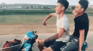 Hình ảnh trong clip 2 thanh niên múa quạt kiểu Khá Bảnh đi xe thả tay.